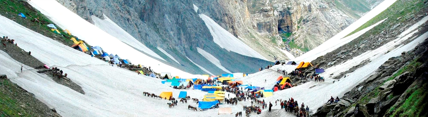Pilgrims on the sacred Amarnath Yatra journey, trekking through the Himalayan terrain with tents and camps set up along the snow-covered route. Amarnath helicopter booking helps devotees reach this divine pilgrimage site conveniently.